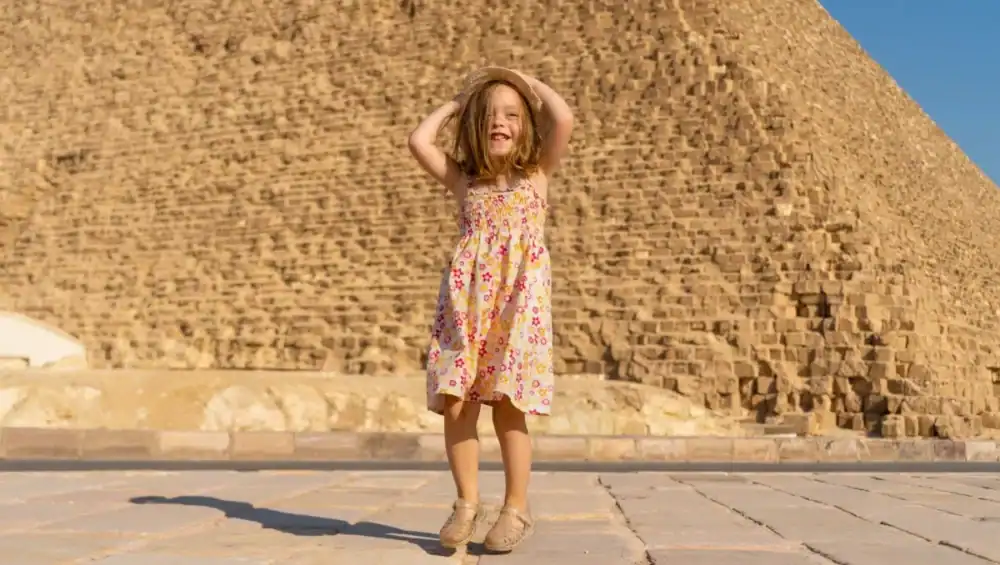 Girl in floral dress near pyramid.